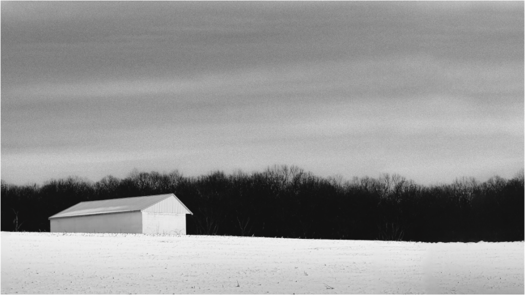 Black and white photograph of open farmland under vast sky—minimalist fine art image emphasizing atmosphere, reduction, and tonal depth.