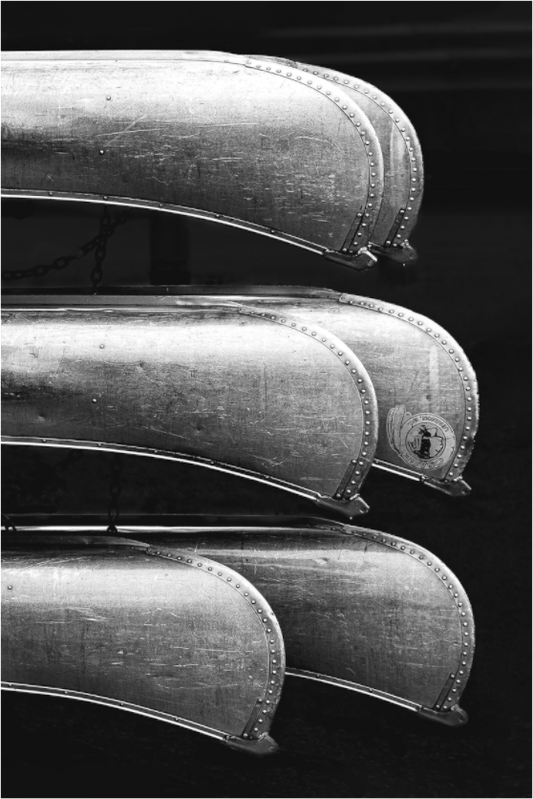 Black and white photograph of rental boats in parallel rows—minimalist composition evoking repetition, rest, and visual harmony.

