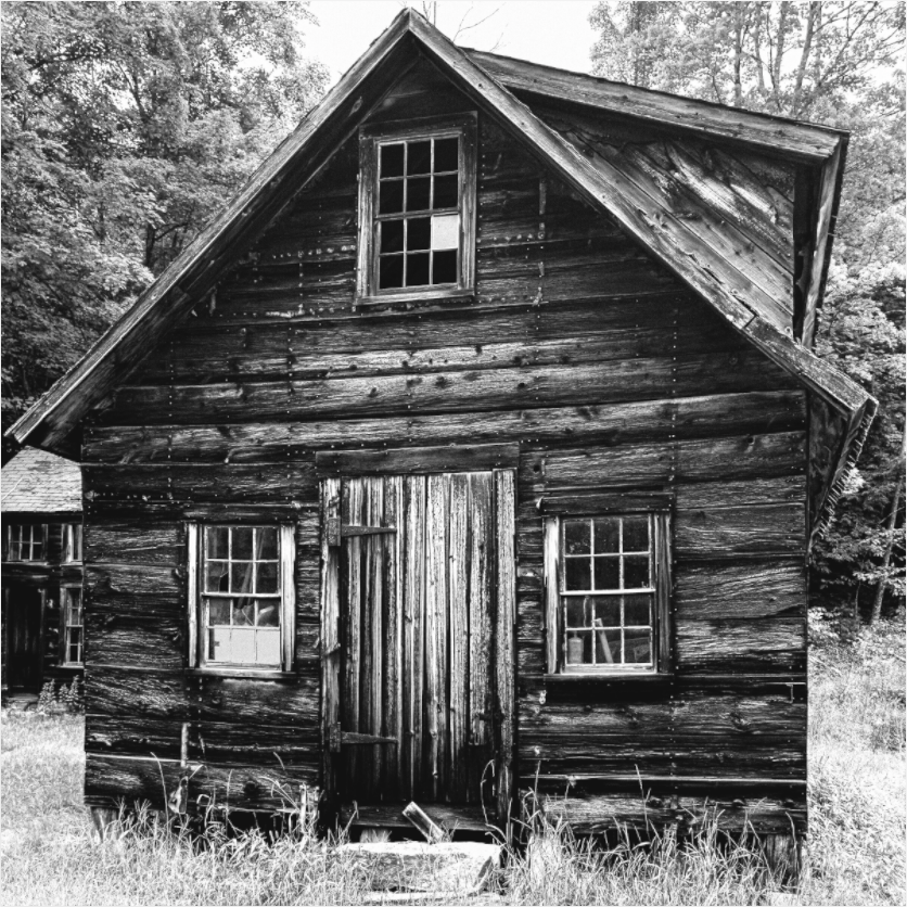 Black and white photograph of an aged wooden barn—textural rural portrait capturing history, resilience, and architectural presence.
