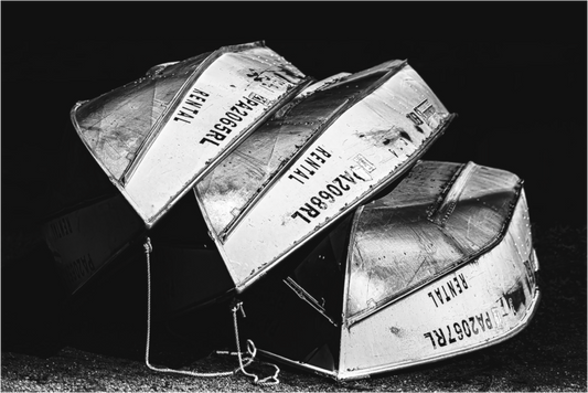 Black and white photograph of a row of rental boats—minimalist composition exploring repetition, shape, and a contemplative sense of order.
